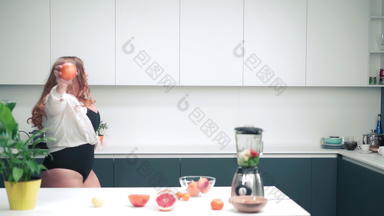 快乐跳舞厨房持有苹果弯曲的身体女孩长金发碧眼的头发穿黑色的泳衣准备新鲜的水果首页使果汁节食营养概念fhd镜头